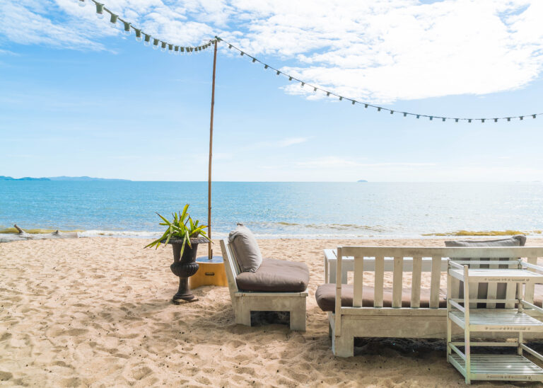 white chairs and table on beach with a view of blue ocean and clear sky