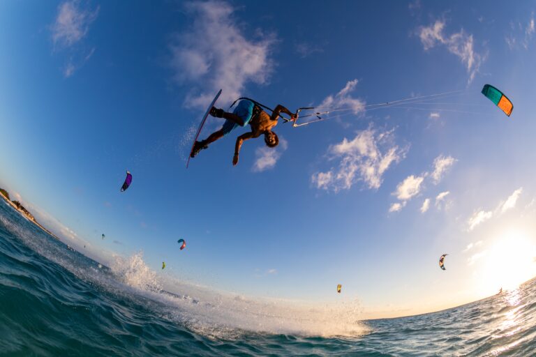 A low angle shot of a person surfing and flying a parachute at the same time in Kitesurfing. Bonaire, Caribbean